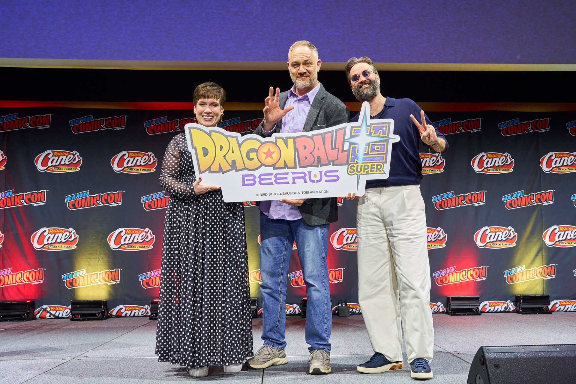 Monica Rial, Jason Douglas e Ian Sinclair segurando o logotipo de Dragon Ball Super: Beerus no palco da New York Comic Con 2026